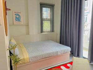 a small bedroom with a bed and a window at Corgi House Central Nha Trang in Nha Trang