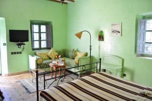 una camera verde con un letto e un divano di Hotel Dar Zitoune Taroudant a Taroudant