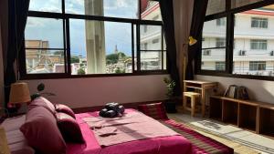 1 dormitorio con cama rosa y ventanas grandes en Baan PadSeeEw - Rooftop Riverview 3rd floor, en Thonhuri