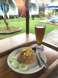 Un plato de comida en una mesa con un vaso de cerveza. en Megaland Bungalow, en Nusa Penida