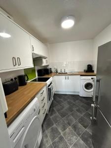 a kitchen with white cabinets and a washer and dryer at One bed Apartment with Parking in Seaford