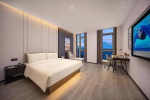 Atour Hotel Wuhan Hankou Riverside Park, Jiefang Avenue في Jiang'an: غرفة نوم بها سرير أبيض كبير ومكتب