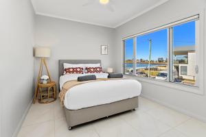 a bedroom with a large bed and a large window at Seabreeze on the Beach in Barrack Point
