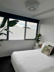 a bedroom with a white bed and a large window at Centrepoint Units Heidelberg in Melbourne