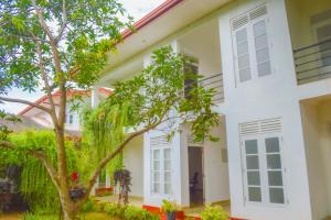 a white house with a tree in front of it at Hotel Water Nest in Etagama
