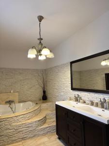 Un baño con bañera, lavabo y espejo. en Villa Viktória, en Lunca de Sus