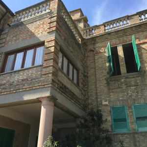 a brick building with green windows and a pillar at Appartamento Esmeralda in Tortoreto Lido