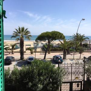 a parking lot with cars and palm trees and the beach at Appartamento Esmeralda in Tortoreto Lido