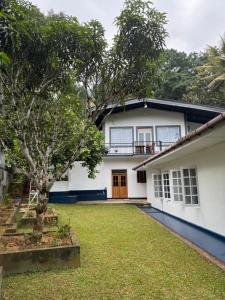 a white house with a tree in the yard at charlotte inn in Gampola