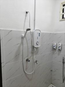 a shower in a bathroom with white tiles at Impian homestay, wcy in Kota Bharu