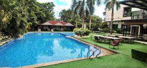 Una piscina con mesas y sillas al lado de un edificio. en Dancenter Luxury Retreat Angeles City Pampanga Formerly Hevea Resort, en Ángeles 83 fotos más