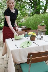 Eine Frau steht an einem Tisch mit einem Tischtuch. in der Unterkunft Landgasthof Löwen in Oberopfingen