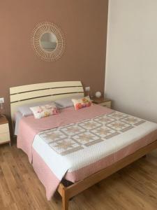 a bedroom with a bed with a pink blanket and a mirror at B&b ARCOBALENO - 2 min walk to Bernina Express in Tirano