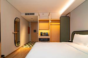 a small bedroom with a bed and a mirror at ARTOTEL Living World Kota Wisata 
