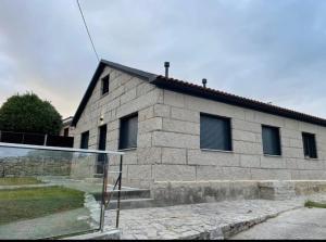a stone building with a tennis court in front of it at Chouciña Apartments in Sanxenxo