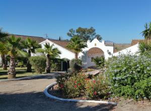 a white house with palm trees and a driveway at Hotel Cortijo del Arte - Caminito del Rey in Pizarra