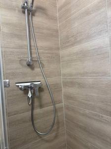 una ducha con una manguera pegada a una pared de azulejos en Ondine, en Gruissan