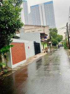 a wet street with a building and tall buildings at Thiago living Syariah in Jakarta +14 photos