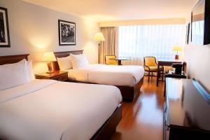a hotel room with two beds and a desk at Radisson Bogota Metrotel in Bogotá