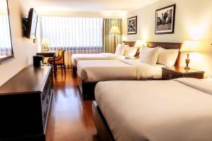 a hotel room with three beds and a desk at Radisson Bogota Metrotel in Bogotá