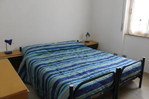 アルゲーロにあるAppartamento La Palmaのベッドルーム1室(ストライプ毛布付きのベッド1台付)