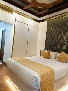 a bedroom with a large white bed with yellow pillows at Hotel Royal Stay - Abraham Pandither Road in Thanjāvūr