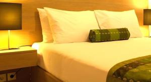 塞米亚克Eazy Suite Legian的一张位于酒店客房的床铺,上面有绿色枕头 更多37张照片