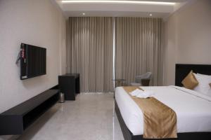 a hotel room with a bed and a television at Alba Regency in Guruvāyūr +35 photos
