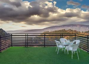 a table and chairs on a balcony with a view at ExoticStays l Empire Kasauli in Kasauli