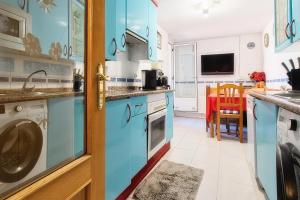 a kitchen with blue cabinets and a washer and dryer at Vivienda turística Felicia in León +18 photos