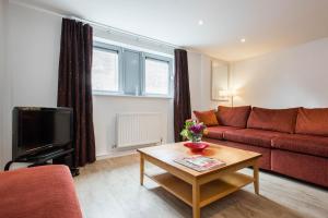 a living room with a red couch and a table at PREMIER SUITES Newcastle in Newcastle upon Tyne