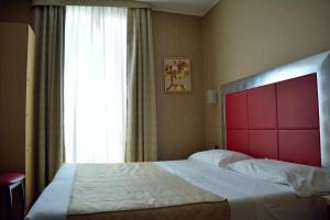 a bedroom with a large bed with a red headboard and a window at Hotel Susa in Milan