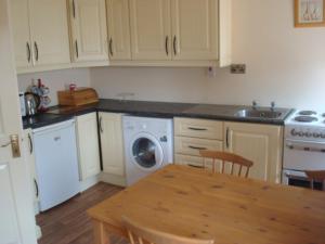 a kitchen with a table and a washing machine at Swinford Bridge Street Apartment in Swinford