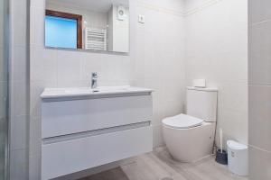 a white bathroom with a sink and a toilet at Vivienda Turística Osiris in San Andrés del Rabanedo