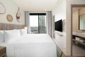a bedroom with a large white bed and a television at Staybridge Suites Bangkok Sukhumvit by IHG in Bangkok