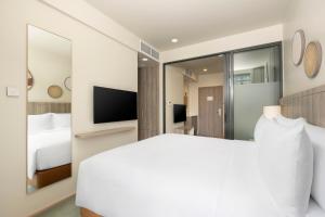 a bedroom with a white bed and a television at Staybridge Suites Bangkok Sukhumvit by IHG in Bangkok