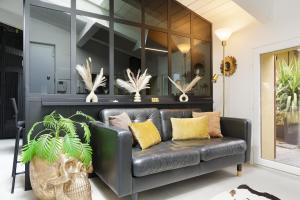 a black leather couch in a room with plants at Tranquility Inn- 25 min Duomo M1 in Sesto San Giovanni +10 photos