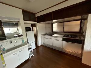 a kitchen with stainless steel appliances and wooden cabinets at Denim-yado Ken-健- in Tamano