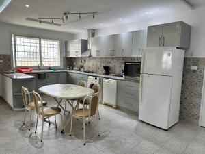 Una cocina con una mesa y un refrigerador blanco. en Villa Azur, en Ḩammām al Ghazzāz