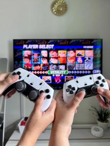 a person holding two video game controllers in front of a tv at Dream Escapade in Manila