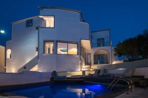 a villa with a swimming pool at night at Sweet Pop in Fira