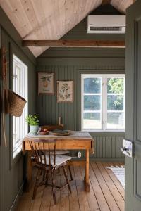 a dining room with a wooden table and two windows at Röhällastugan in Färjestaden +29 photos