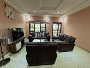 ein Wohnzimmer mit Ledermöbeln und einem Flachbild-TV in der Unterkunft Zachepa Family House in Lilongwe
