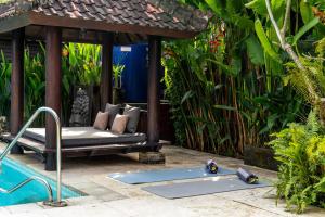a patio with a bed and a swimming pool at Tropical Villa Matahari - 500sqm private Garden Retreat with large Pool! in Uluwatu