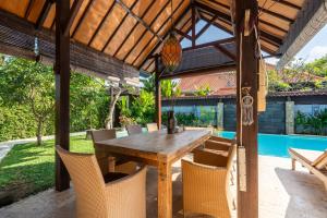 an outdoor dining area with a wooden table and chairs at Tropical Villa Matahari - 500sqm private Garden Retreat with large Pool! in Uluwatu