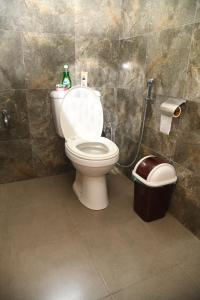 a bathroom with a toilet and a trash can at Traget safari home stay in Udawalawe
