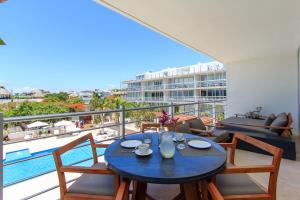 - Balcón con mesa de comedor y sillas y piscina en Gorgeous Magia Beachside Condos by Stella Rentals, en Playa del Carmen