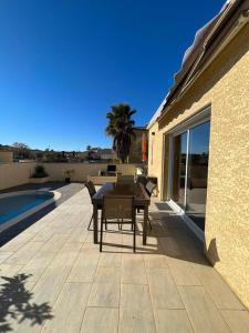 un patio con tavolo e sedie accanto a una casa di Maison avec piscine privée entièrement climatisée a Sauvian