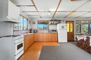 a large kitchen with white appliances and wooden cabinets at Bull Tavern Cabin Cozy Lakeside Escape in Miena Tasmania in Miena