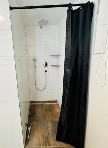 a shower with a black shower curtain in a bathroom at Ferienhaus Waldklause in Schwarzenberg im Bregenzerwald +18 photos